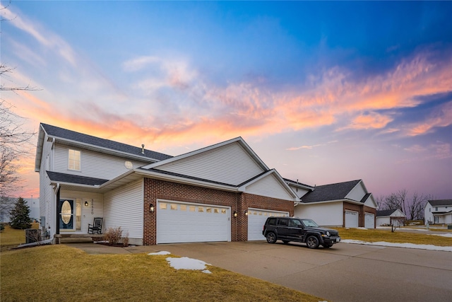 traditional-style house with brick siding, driveway, a front yard, and a garage