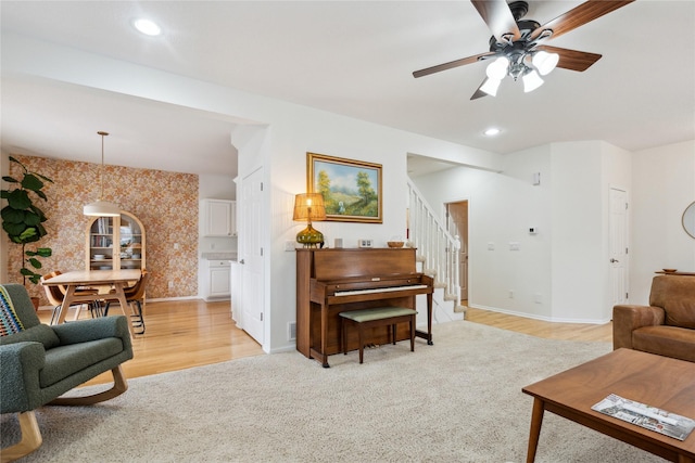 living room with a ceiling fan, recessed lighting, light wood finished floors, baseboards, and stairs