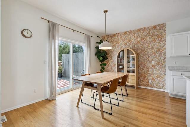 dining area with arched walkways, light wood-style flooring, wallpapered walls, and baseboards