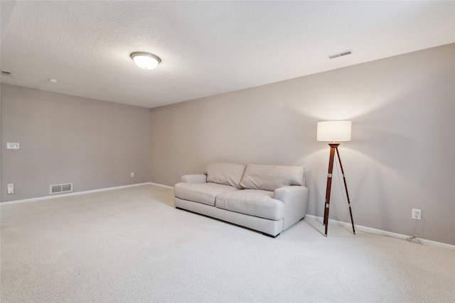 sitting room featuring light carpet, visible vents, a textured ceiling, and baseboards