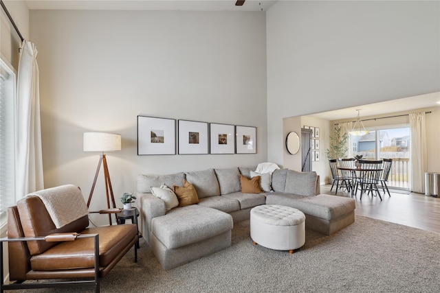 living room featuring a ceiling fan, a towering ceiling, and wood finished floors