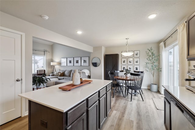 3325 Wolf Creek Rd SW, Bondurant, IA 50035 - kitchen with light countertops, a kitchen island, light wood finished floors, stainless steel dishwasher, and decorative light fixtures