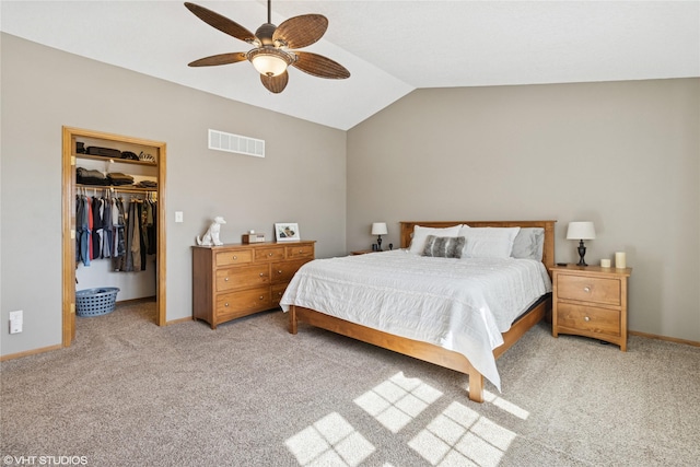 bedroom featuring baseboards, visible vents, vaulted ceiling, light carpet, and a walk in closet