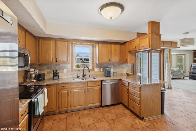 kitchen with a sink, stainless steel appliances, a peninsula, and a wealth of natural light