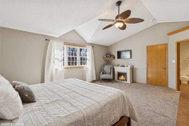 bedroom with baseboards, carpet, vaulted ceiling, a warm lit fireplace, and a ceiling fan