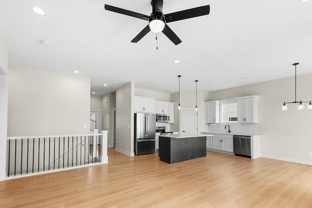 kitchen with light wood-style flooring, a sink, tasteful backsplash, a center island, and stainless steel appliances