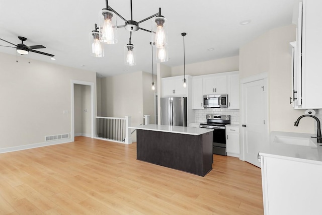 kitchen with visible vents, a sink, backsplash, a center island, and appliances with stainless steel finishes