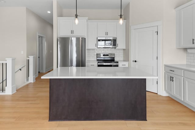 kitchen featuring light wood-style flooring, appliances with stainless steel finishes, white cabinetry, and light countertops