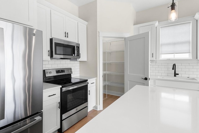 kitchen featuring decorative backsplash, appliances with stainless steel finishes, light countertops, and a sink