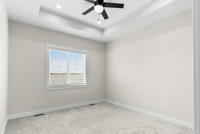 spare room with visible vents, baseboards, a raised ceiling, and carpet