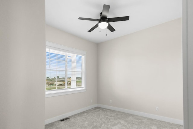 carpeted empty room with visible vents, ceiling fan, and baseboards