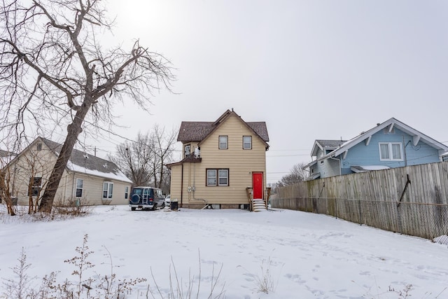snow covered house featuring fence