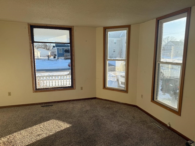 carpeted empty room featuring visible vents, baseboards, and a textured ceiling