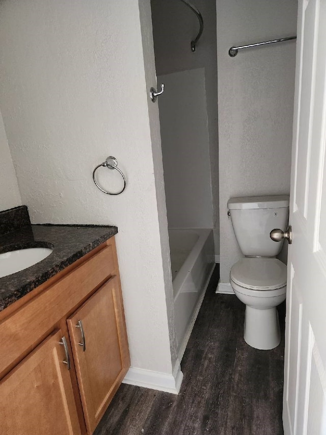 bathroom featuring vanity, wood finished floors, baseboards, shower / bath combination, and toilet