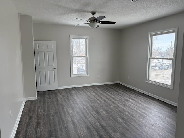 empty room with ceiling fan, a textured ceiling, baseboards, and dark wood-style flooring