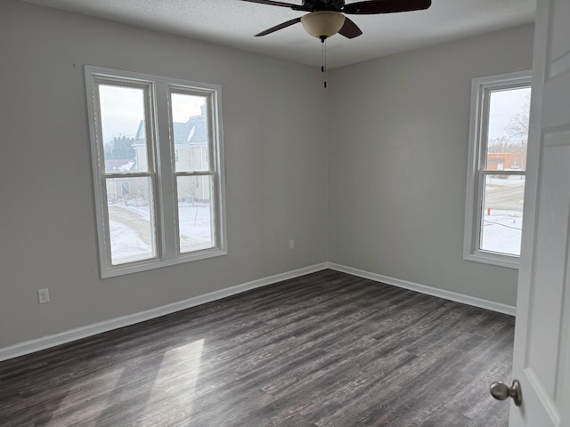 spare room featuring dark wood-style floors, baseboards, and ceiling fan