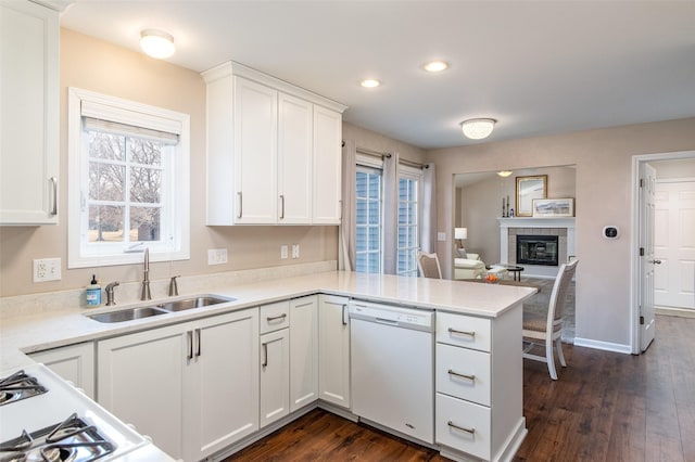 kitchen with dishwasher, light countertops, a fireplace, white cabinets, and a sink