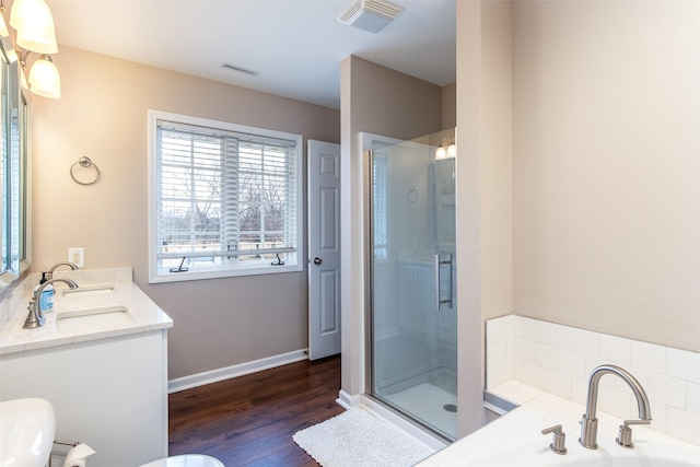 bathroom featuring a bath, visible vents, a shower stall, and wood finished floors