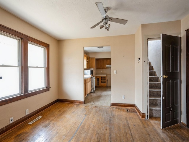 unfurnished living room with stairway, baseboards, light wood-style floors, and visible vents