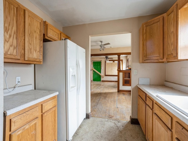 kitchen with white refrigerator with ice dispenser, light countertops, ceiling fan, and a sink