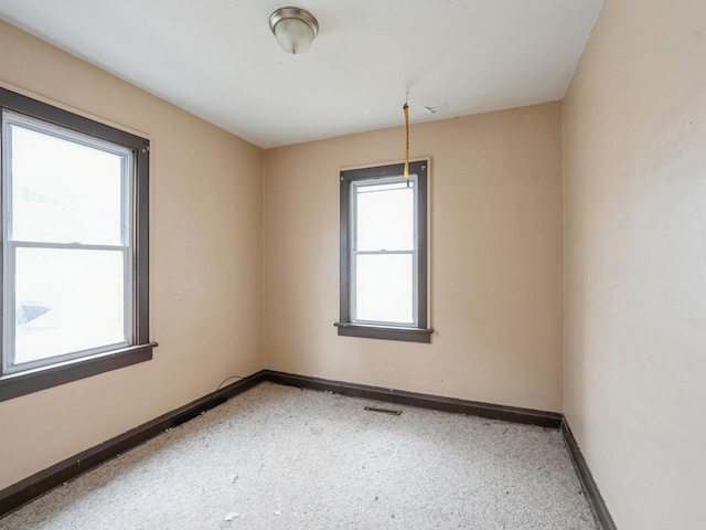 spare room featuring a wealth of natural light, visible vents, and baseboards