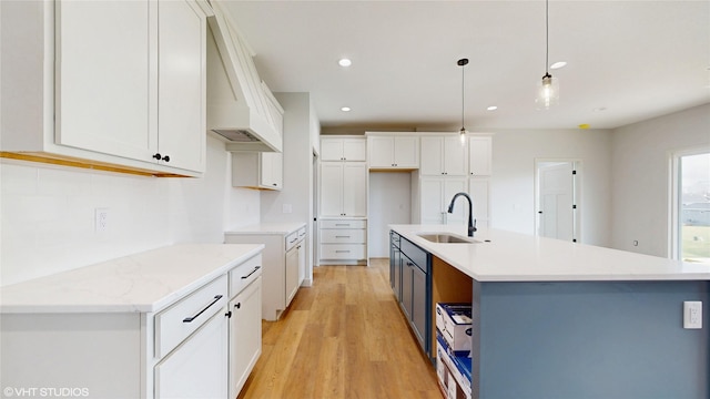 202 Meadowlark Dr, Monroe, IA 50170 - kitchen with a sink, light wood-style floors, white cabinetry, an island with sink, and pendant lighting