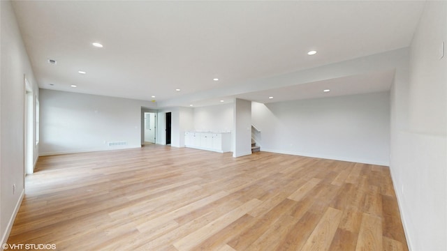 unfurnished living room with stairs, recessed lighting, light wood-type flooring, baseboards, and visible vents
