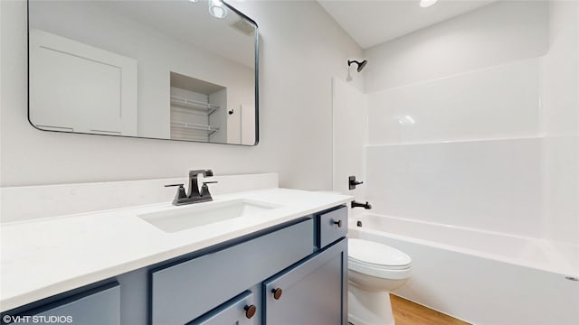 full bath featuring toilet, shower / bath combination, vanity, and wood finished floors