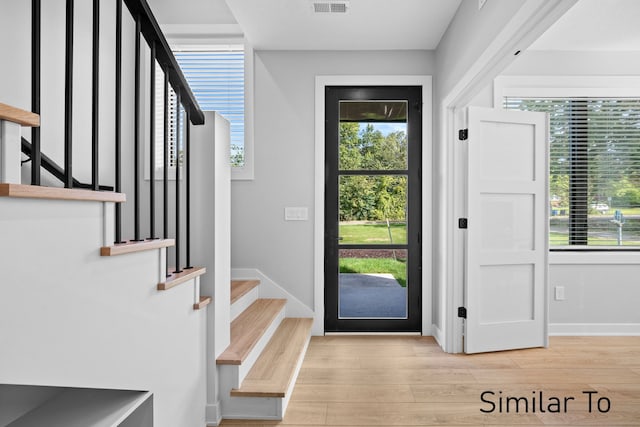4828 Ingersoll Ave, Des Moines, IA 50312 - entryway with visible vents, baseboards, stairs, and light wood-style floors