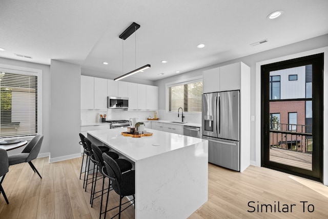 4828 Ingersoll Ave, Des Moines, IA 50312 - kitchen with a kitchen island, a breakfast bar area, light countertops, appliances with stainless steel finishes, and a sink