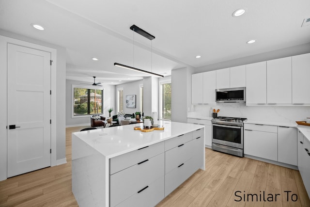 4828 Ingersoll Ave, Des Moines, IA 50312 - kitchen featuring light wood-type flooring, stainless steel appliances, modern cabinets, and white cabinetry