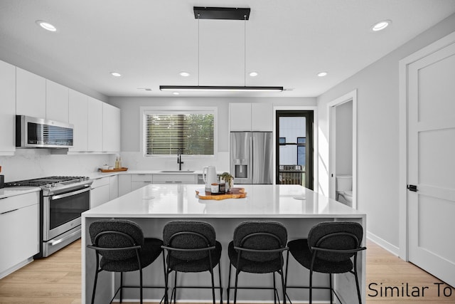 4828 Ingersoll Ave, Des Moines, IA 50312 - kitchen with a sink, stainless steel appliances, a kitchen breakfast bar, and white cabinets