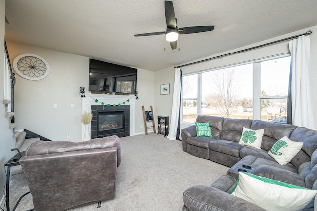 living area with carpet floors, a textured ceiling, stairs, and a tile fireplace