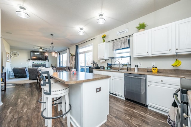 kitchen with dark wood-type flooring, a sink, a breakfast bar area, a fireplace, and dishwasher