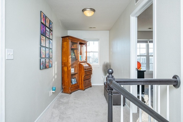 corridor featuring visible vents, an upstairs landing, carpet, and baseboards