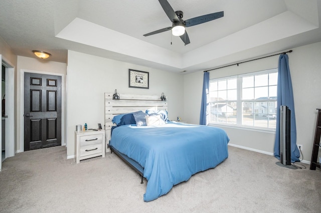 bedroom featuring baseboards, a raised ceiling, carpet, and a ceiling fan