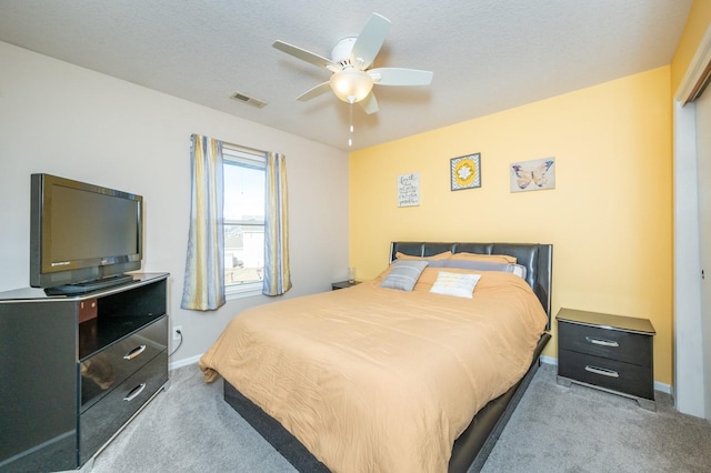 carpeted bedroom featuring visible vents, baseboards, a textured ceiling, and ceiling fan