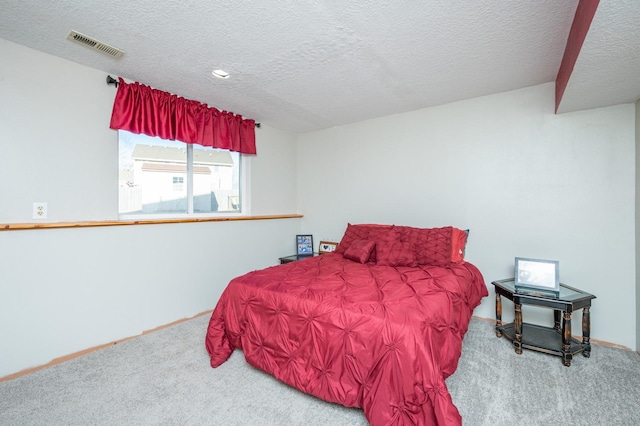 bedroom featuring visible vents, carpet, and a textured ceiling