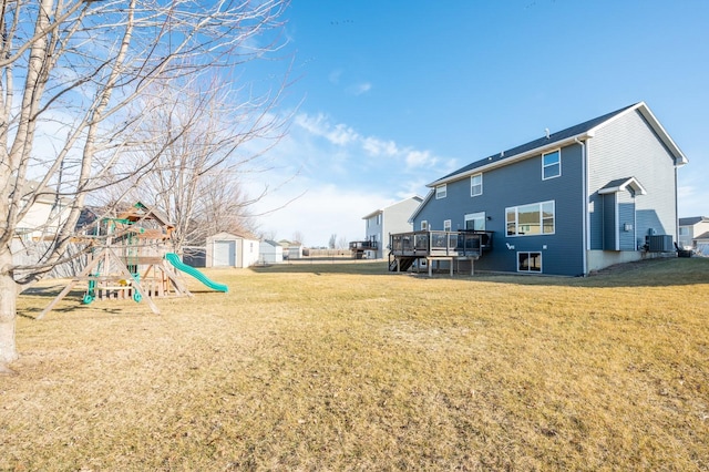 view of yard with central air condition unit, an outbuilding, a deck, and a playground