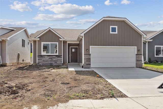 2917 Jerry St, Van Meter, IA 50261 - view of front facade featuring stone siding, board and batten siding, concrete driveway, an attached garage, and roof with shingles