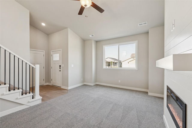 2917 Jerry St, Van Meter, IA 50261 - unfurnished living room featuring stairs, a ceiling fan, a glass covered fireplace, carpet flooring, and recessed lighting