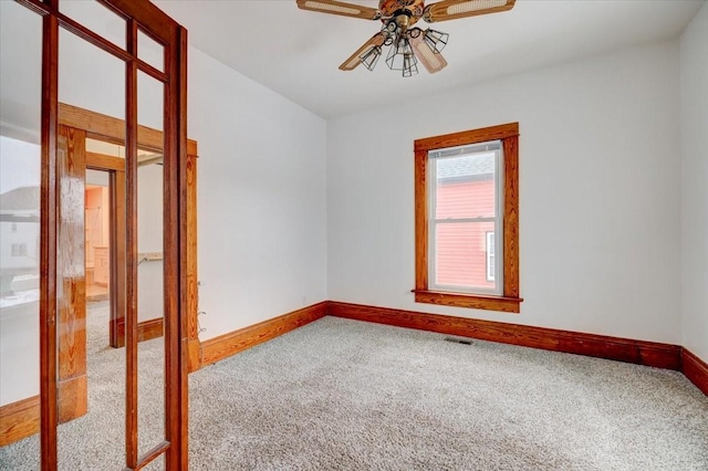 carpeted empty room with baseboards, visible vents, and ceiling fan