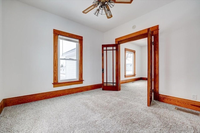 unfurnished room with a ceiling fan, baseboards, and carpet floors