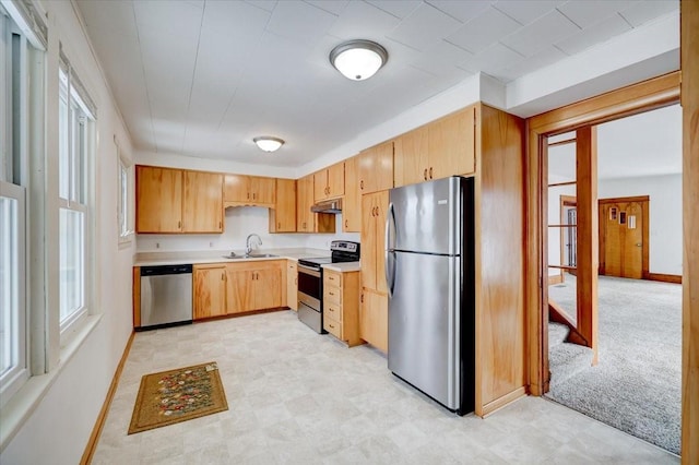 kitchen featuring under cabinet range hood, light floors, light countertops, stainless steel appliances, and a sink