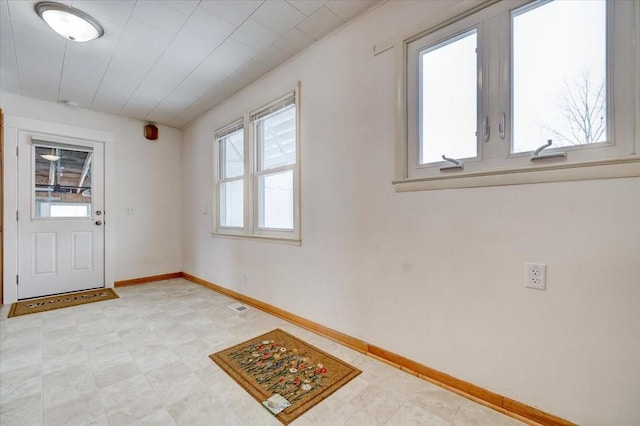 foyer entrance with visible vents, plenty of natural light, light floors, and baseboards