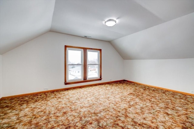 additional living space featuring visible vents, carpet, baseboards, and vaulted ceiling