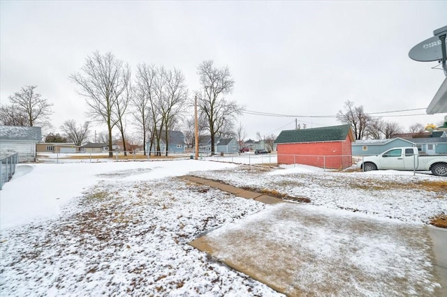 snowy yard featuring a residential view and fence