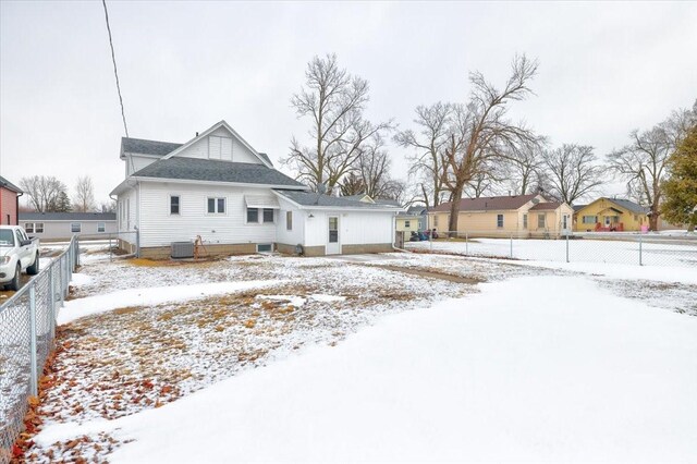 snow covered back of property with cooling unit and fence