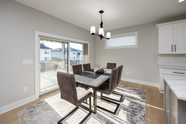 dining area featuring light wood-type flooring, baseboards, a chandelier, and vaulted ceiling