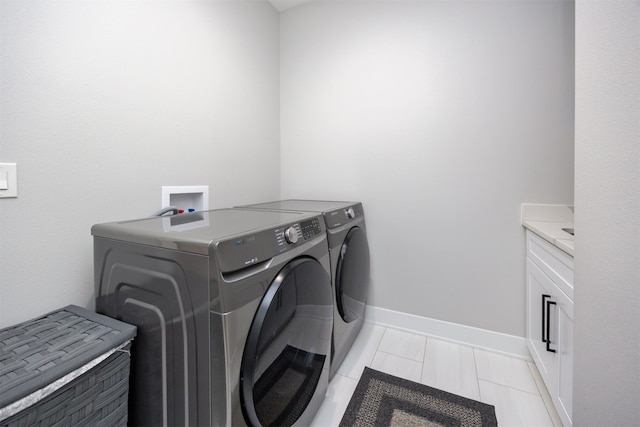 washroom featuring cabinet space, baseboards, and washer and clothes dryer